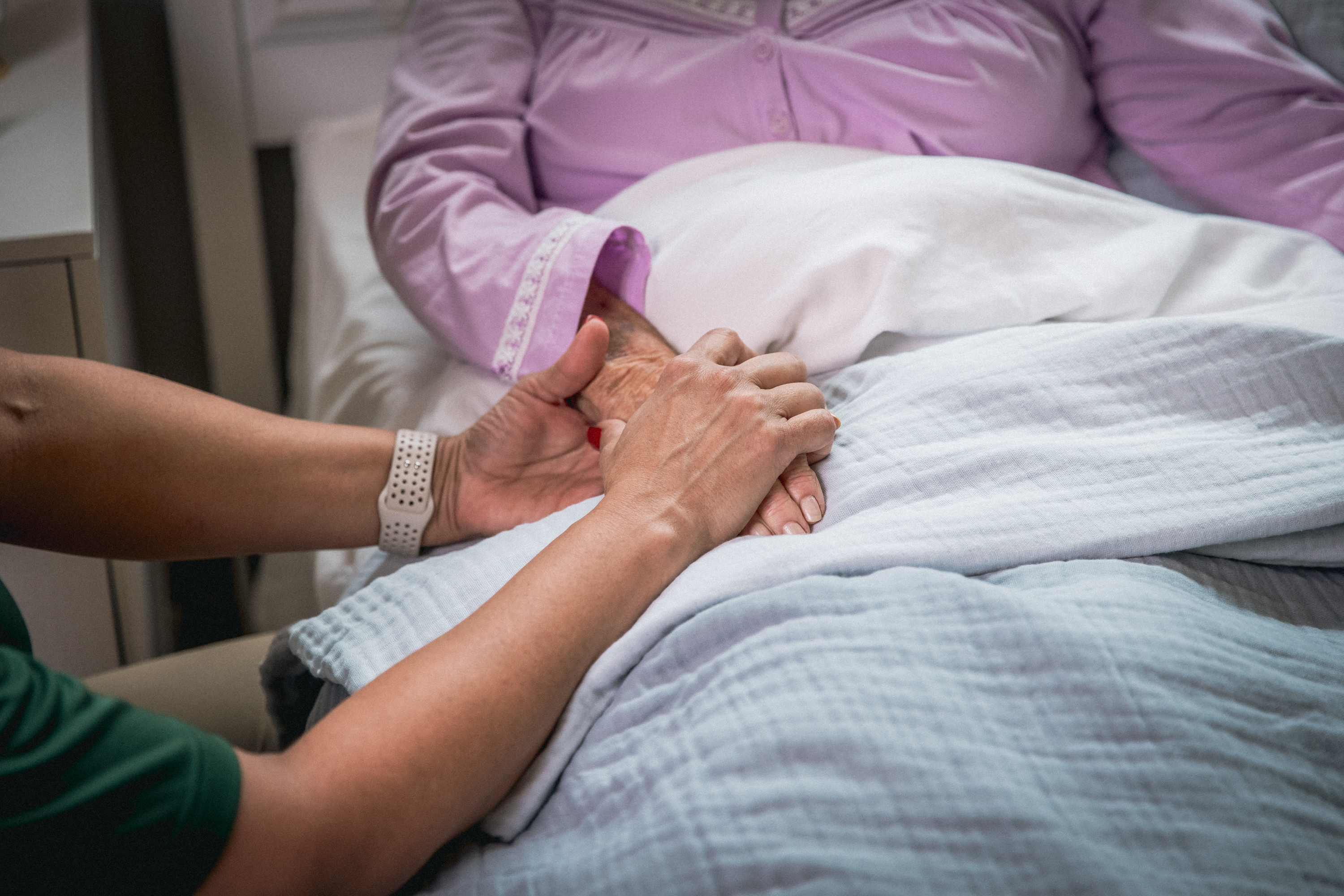 Caregiver gently holding a senior's hands