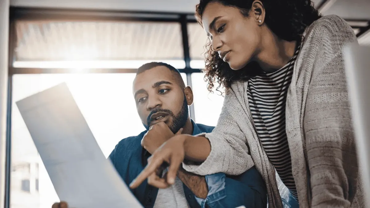 Two business professionals analyzing a complex insurance policy document to spot exclusions and limits for a property claim