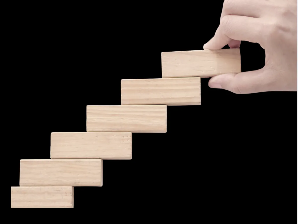 Wooden blocks being intentionally stacked to represent building trust, creating value, and practicing managing up with integrity.