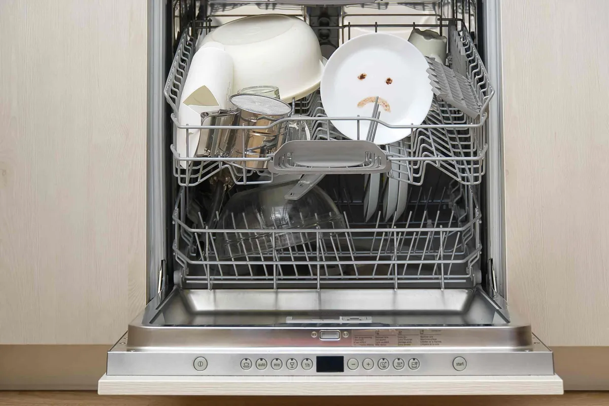 open dishwasher with a plate with a sad face