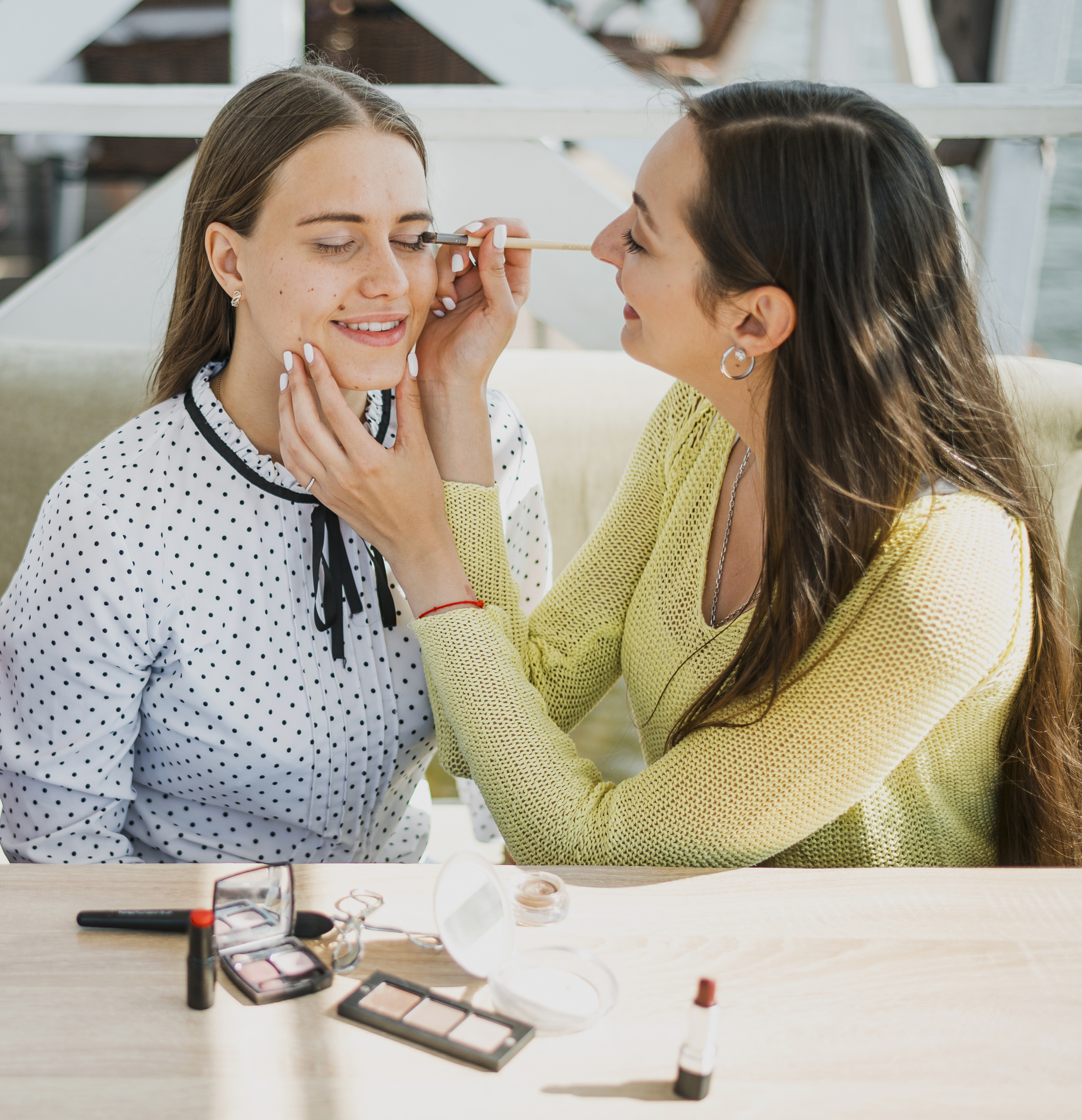 Beauty school student applying makeup to a model during cosmetology training