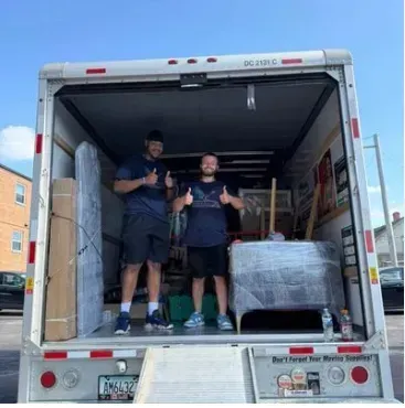 Professional movers carrying boxes and furniture during a residential move.