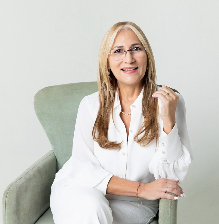 Portrait of a professional woman in her 40s, confident smile, business attire, bookshelf and plants in background, warm lighting, 1:1 aspect ratio