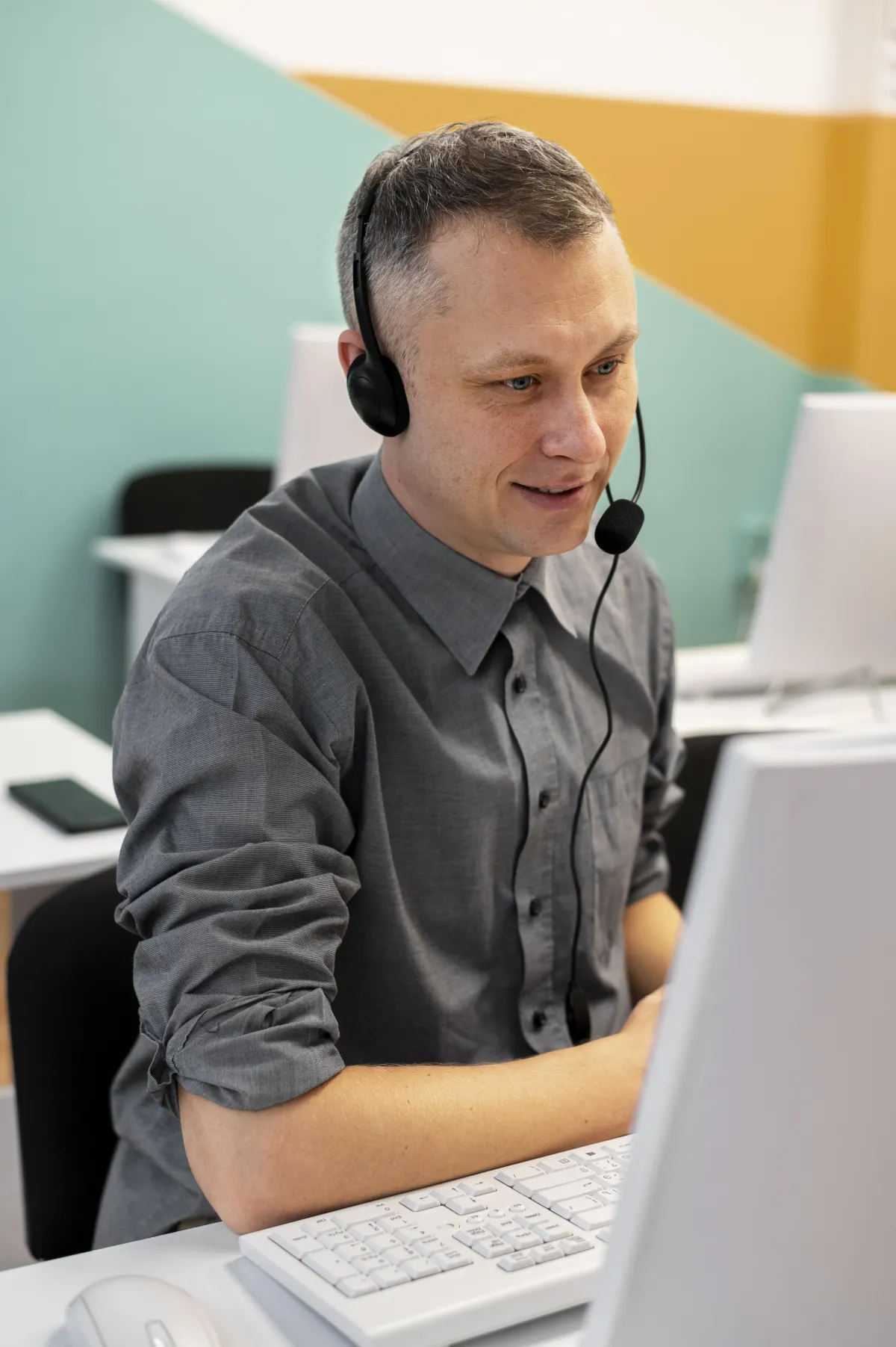 a man sitting at a desk talking on a cell phone