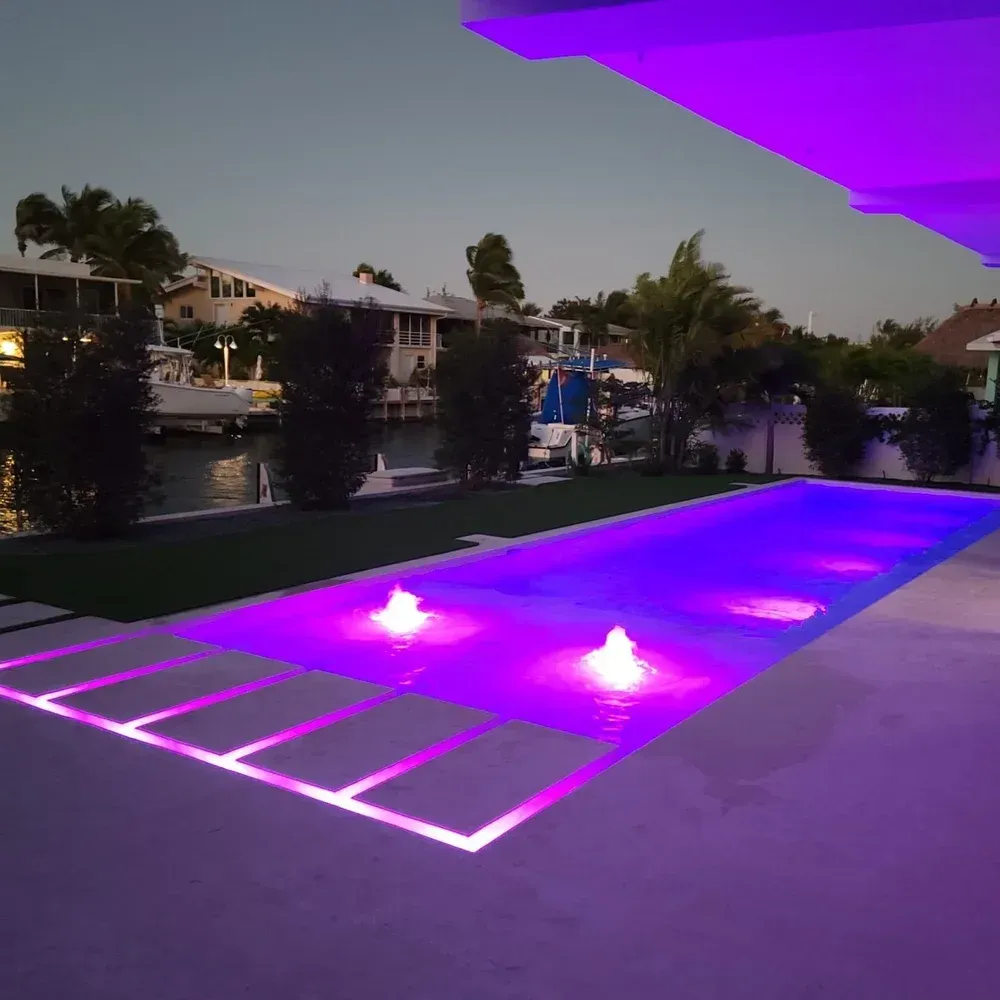 Pool lighting installation with vibrant LED lights illuminating pool at night - Gables Pool lighting design Miami