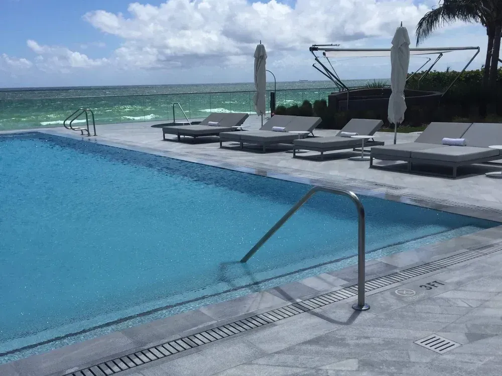 Commercial infinity pool with ocean view lounge chairs and umbrellas Miami - commercial pool maintenance by Gables Pool