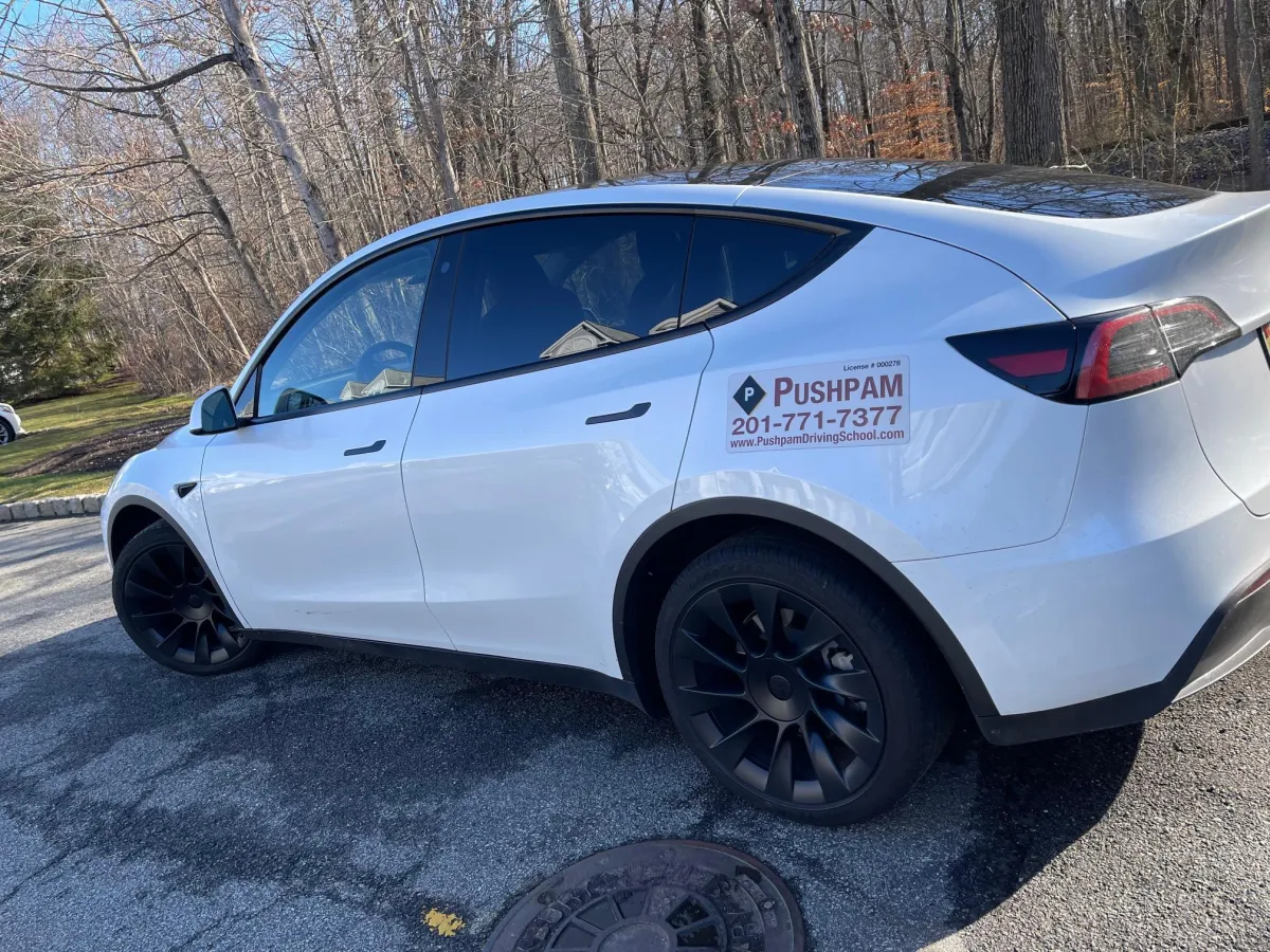 White Tesla with Pushpam Driving School Logo