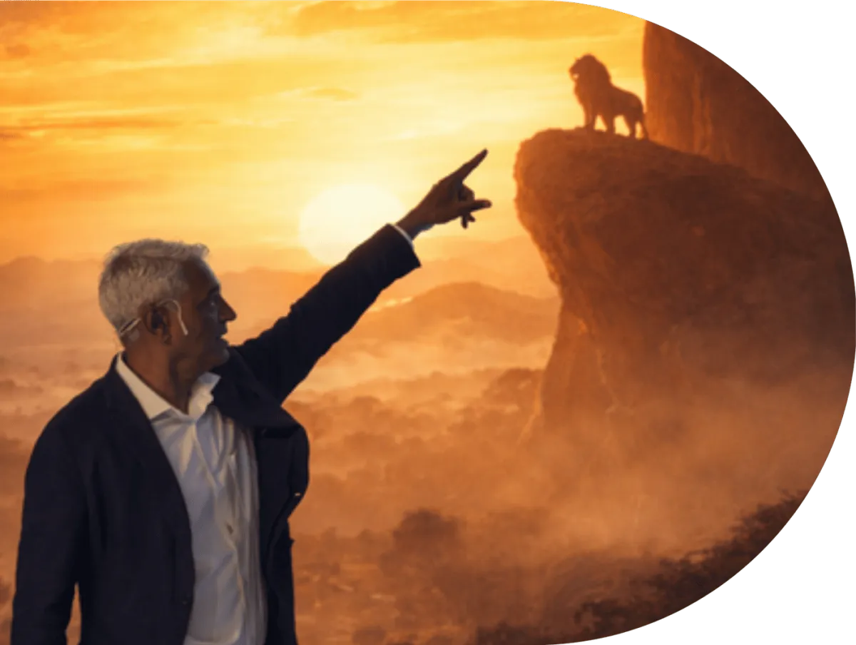 A man pointing towards a lion silhouetted on a rock at sunrise