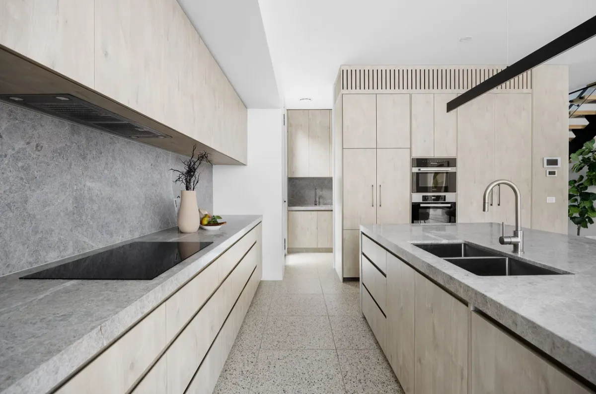 Minimalist renovated kitchen with light cabinetry and stone worktops