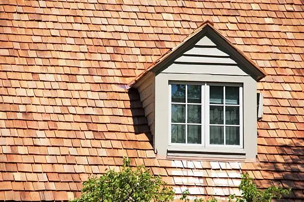 Charming cedar shingle roofing on a suburban house, highlighting natural beauty and durability.