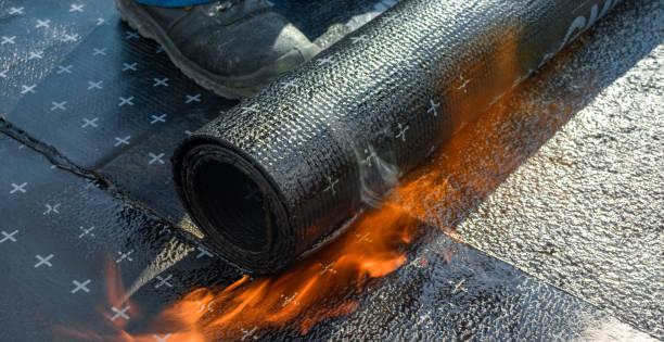 Expert roofer torching a waterproof layer on a flat roof installation