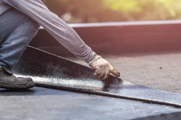 Roofer applying sealant for flat roofing installation