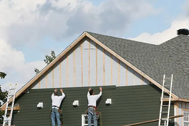 Skilled workers providing full-service siding solutions on a house exterior.