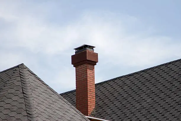 Intact chimney atop a house with grey shingle roofing, symbolizing the results of professional repair and maintenance by Home Star Roofing