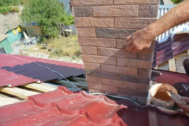 Roofing professional from Home Star Roofing repairing red tile roofing and chimney brickwork, showcasing skilled masonry services.