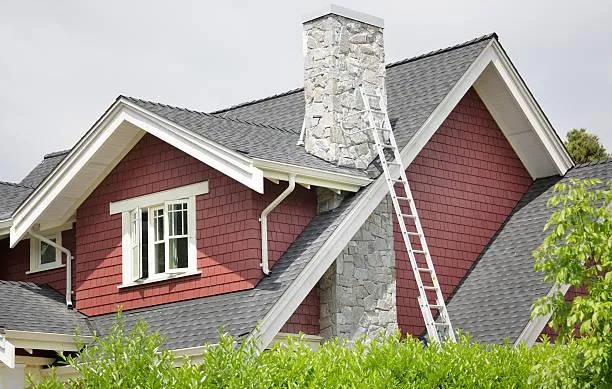 Restored chimney on a house with red siding, exemplifying Home Star Roofing's commitment to preserving home safety and architectural charm.