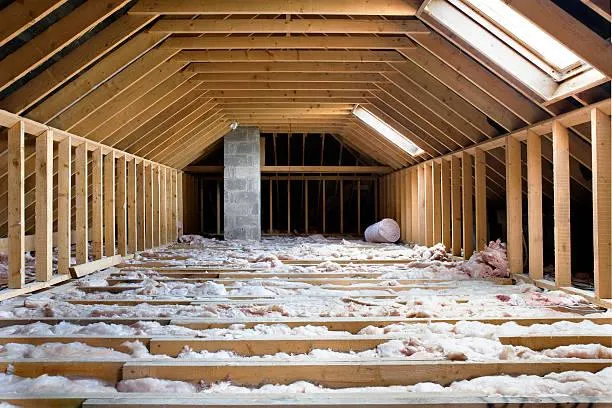 Exposed attic insulation between wooden rafters, illustrating the type of insulation services provided by Home Star Roofing.