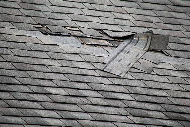 Damaged roof shingles lifted up, indicating the need for repair services provided by Home Star Roofing.