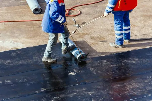 Workers applying new material during a commercial flat roof replacement, illustrating Home Star Roofing's professional service.