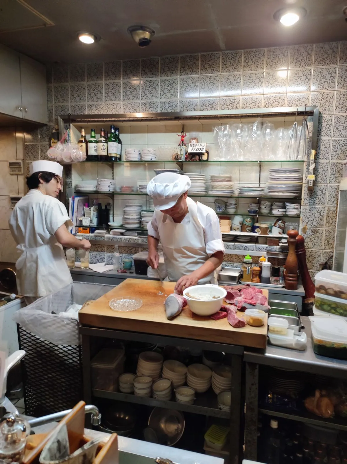 Two chefs preparing plates in a busy restaurant kitchen during service
