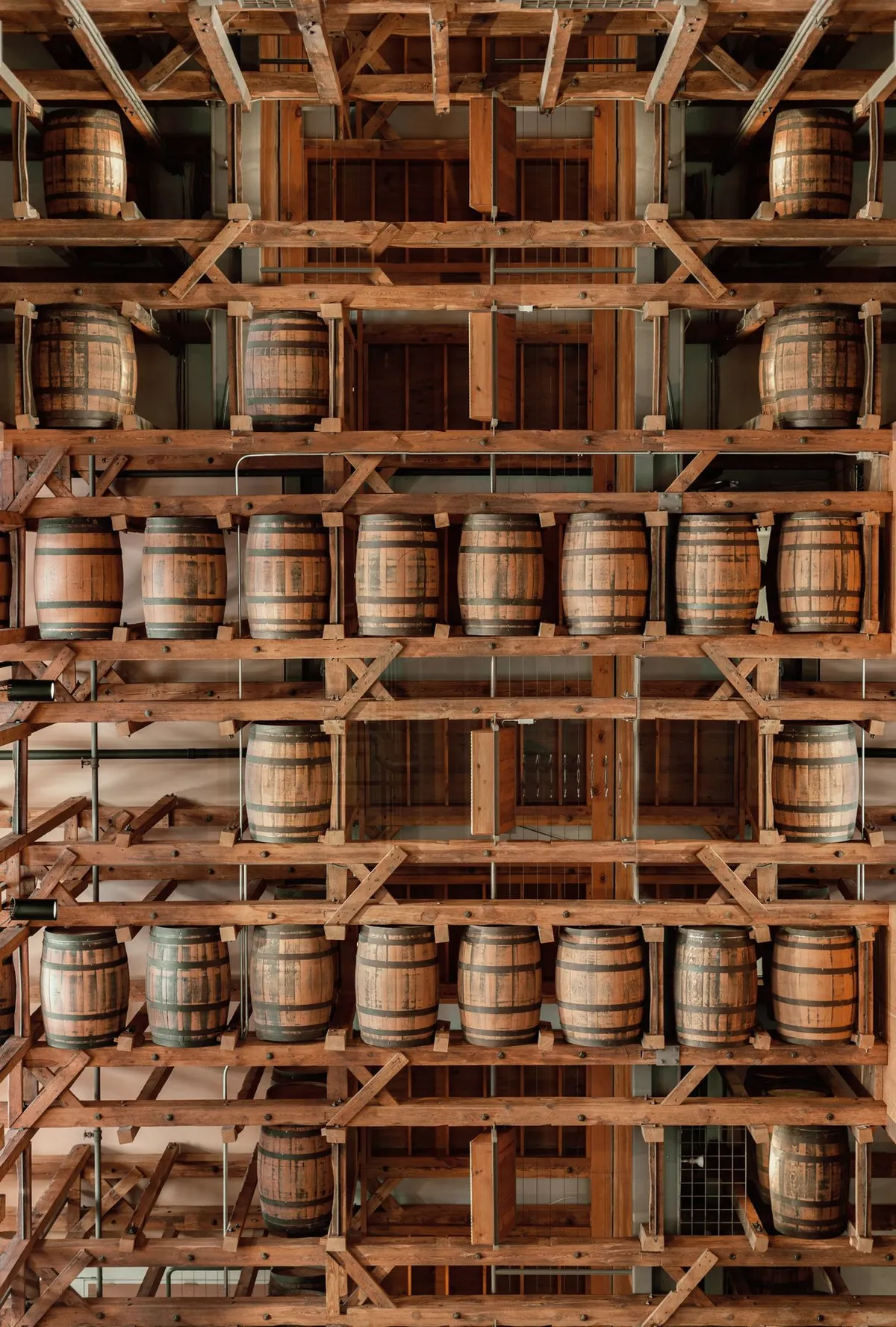 Wooden bourbon barrels stacked on racks in a distillery rickhouse