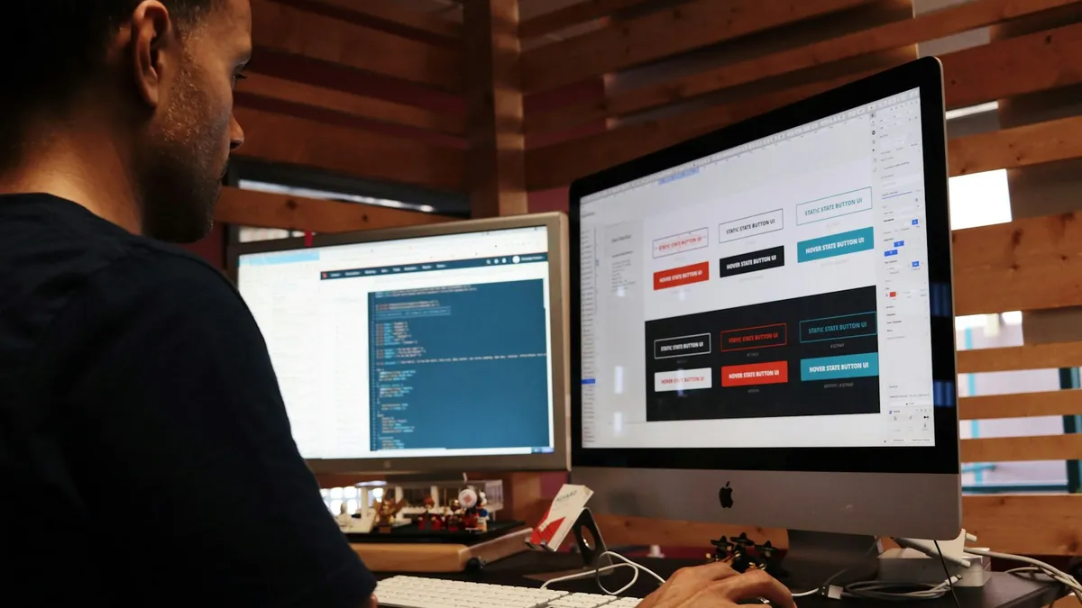 Person comparing two software screens on a pair of desktop monitors