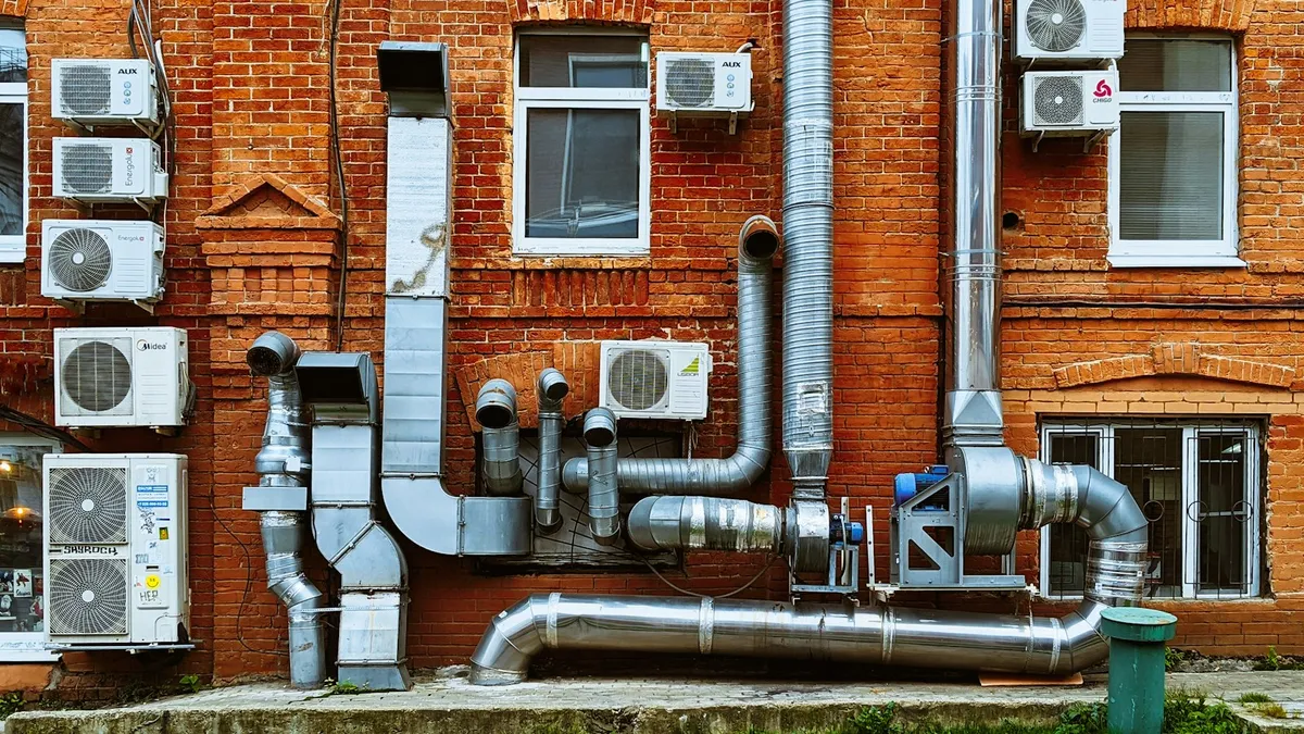 Air conditioning units and ductwork on the side of a brick building