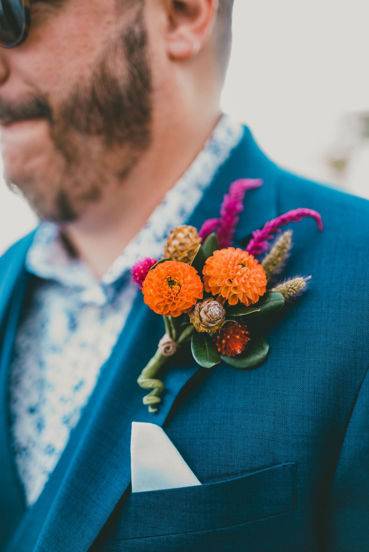 A textural groom's boutonniere with mini cornell bronze dahlias, celosia, dried grass, and gomphrena,