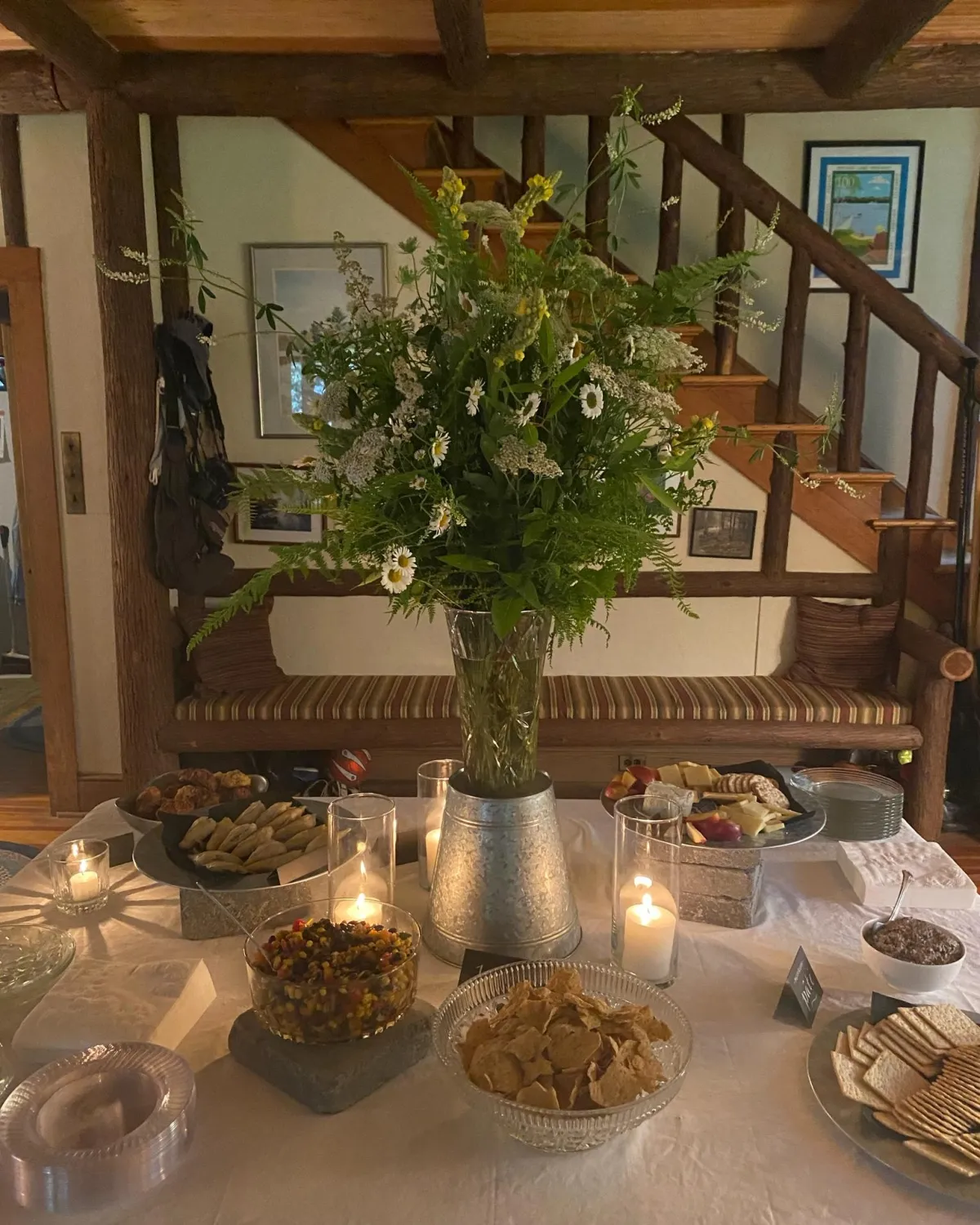 A large buffet centerpiece of July foraged flowers and foliage in white and yellow with lots of natural greenery.