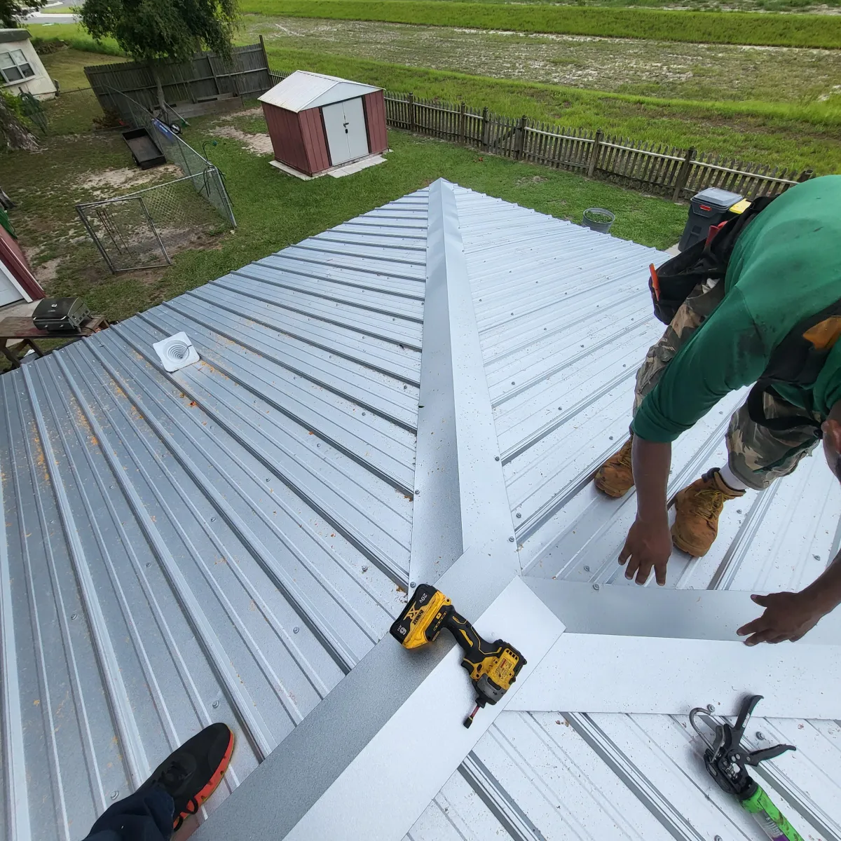 Roofing crew installing standing seam metal panels on residential roof.