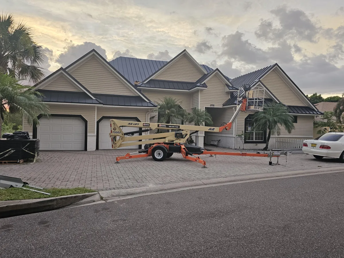 Steep-slope metal roof home with mobile boom lift staged for roofing work in Polk County.