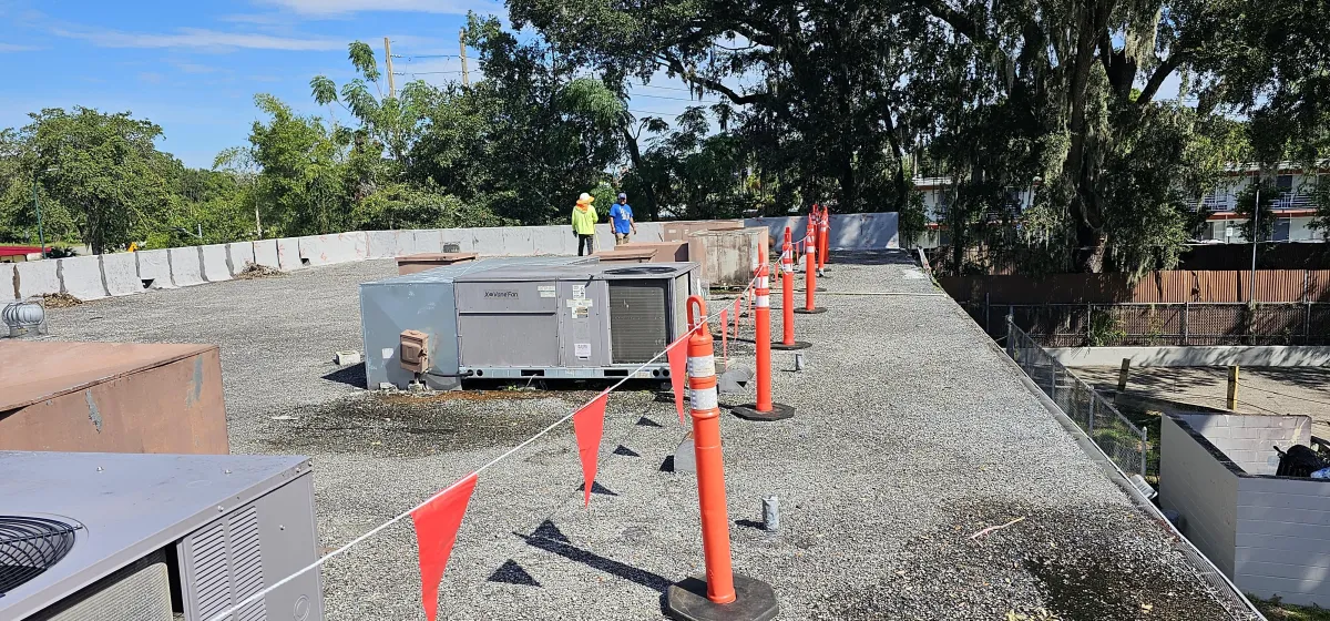 Gravel-surfaced roof with safety flags and rooftop HVAC units during inspection.