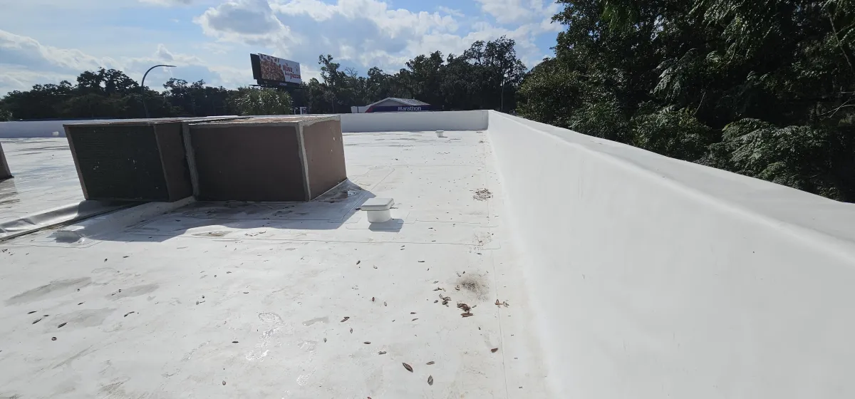 White coated flat roof with parapet wall and HVAC curb.