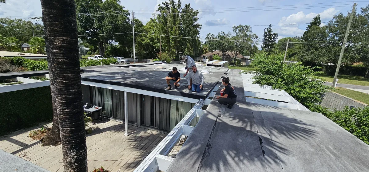 Crew installing new flat roofing membrane on a residential flat/carport roof.