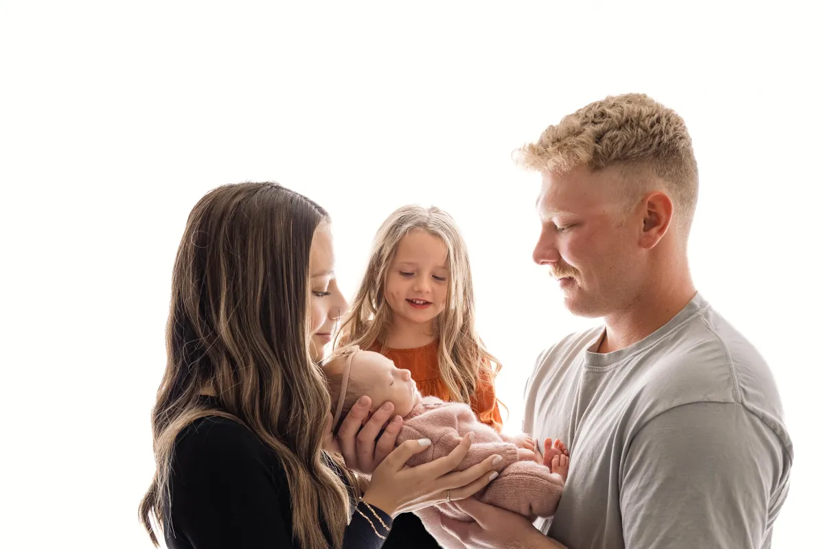 parents and sister looking at baby