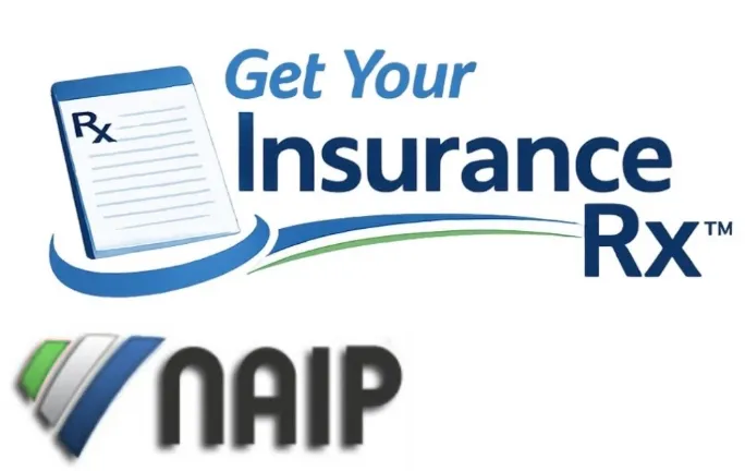 A skier performs a trick mid-air over snowy trees.