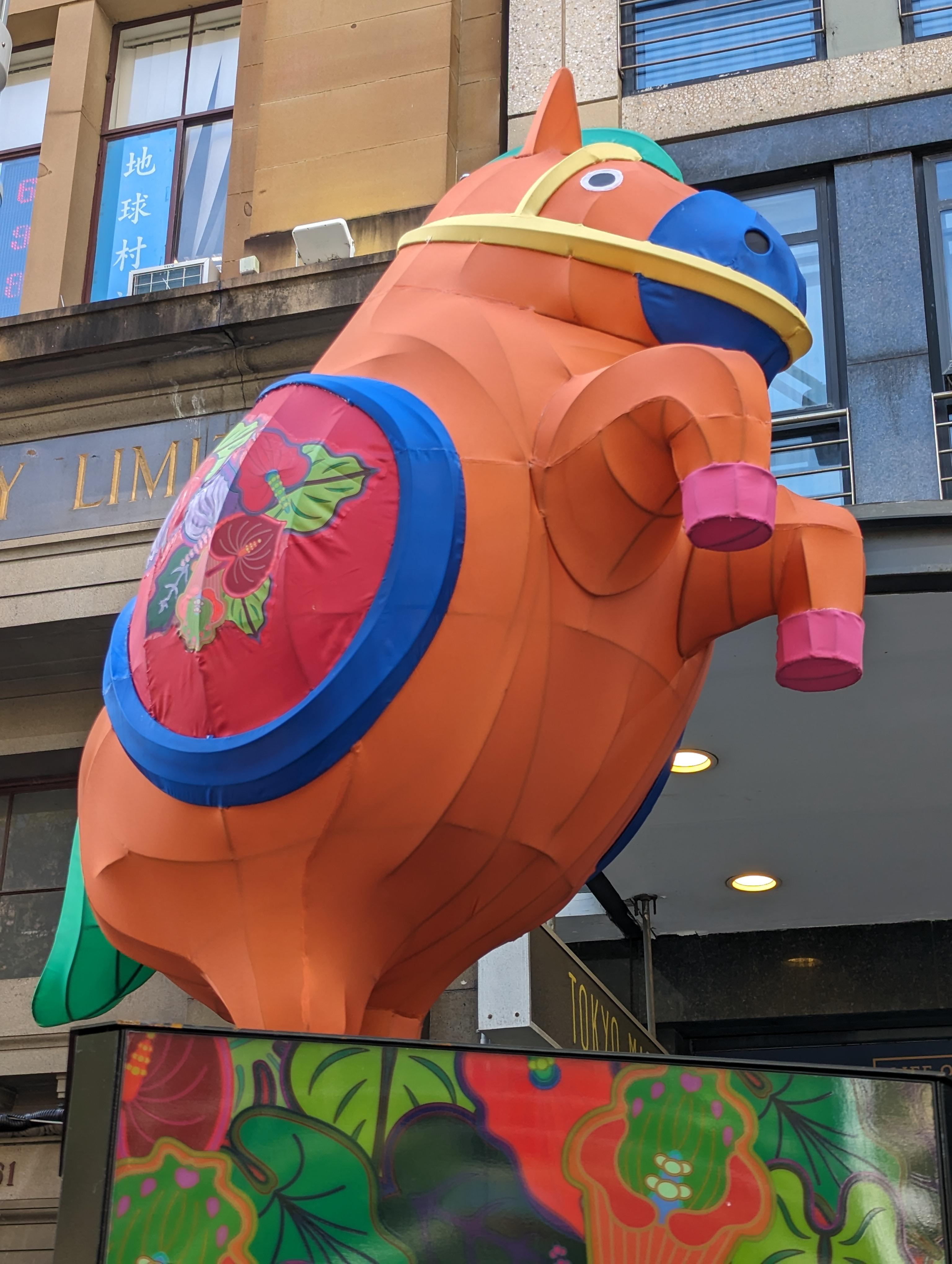 A colourful Chinese new year character depicting an orange model horse on a plinth.