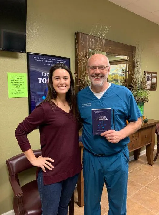 Dr. ndy Barlow Chiropractor holding license to heal book