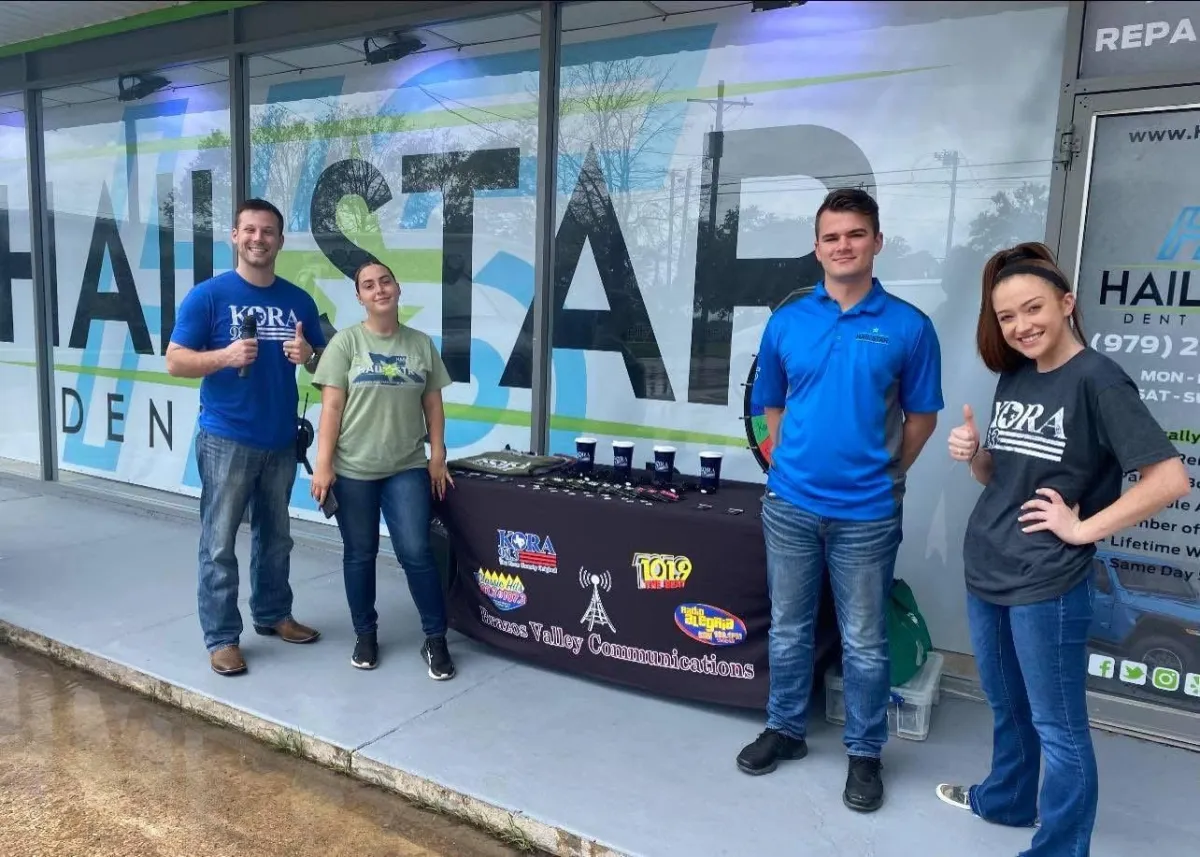 Smiling technician holding tools in a ForgeFix Auto workshop bay