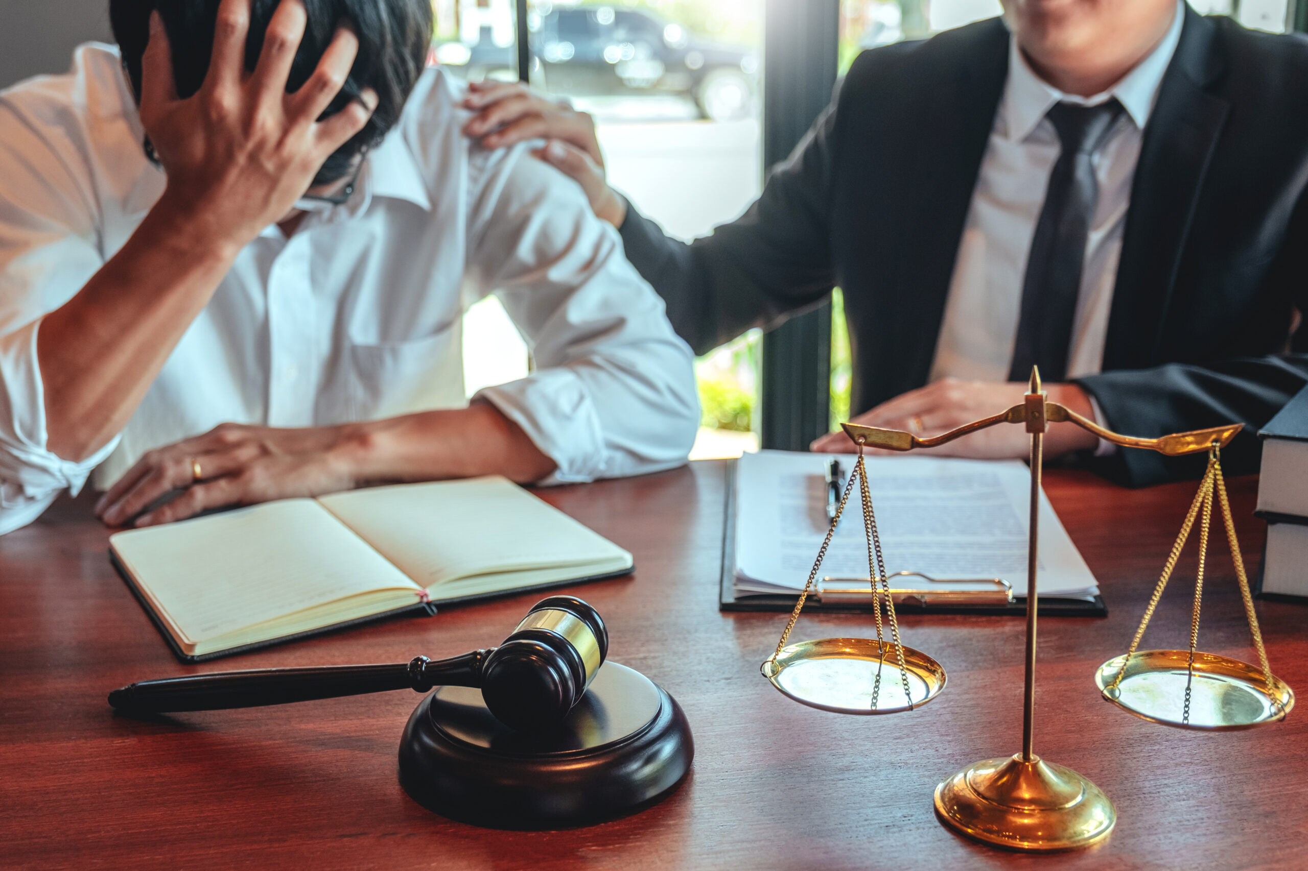 Client in distress consulting with attorney at a desk with legal books and scales of justice, symbolizing legal services for creditors in bankruptcy cases.