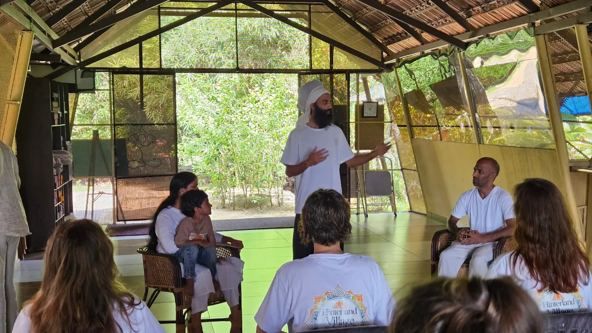 Group of people practicing yoga in an open wooden pavilion surrounded by nature.