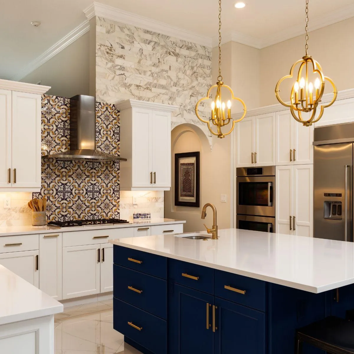 Modern kitchen featuring white cabinetry, gold accents, and a decorative backsplash, highlighting a spacious island with a sleek countertop, ideal for showcasing home features in real estate marketing.