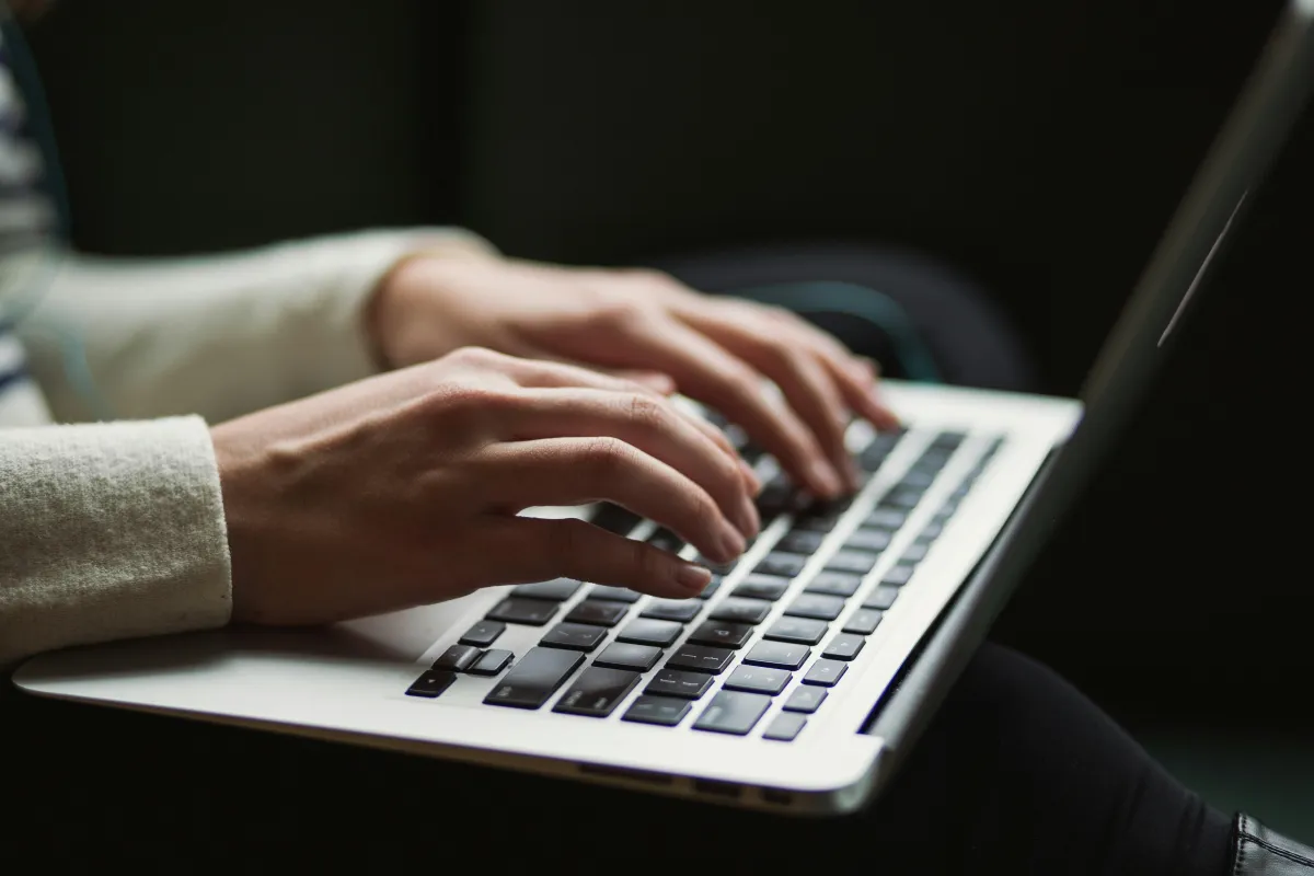 Hands typing on a laptop as IT removes local admin rights to reduce support tickets