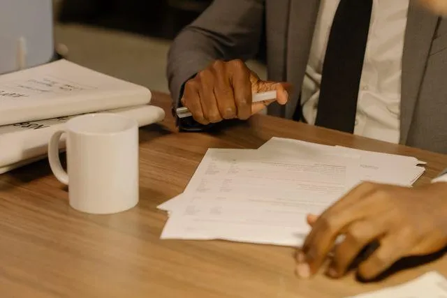 Close-up of a businessman holding and reviewing documents on a wooden desk