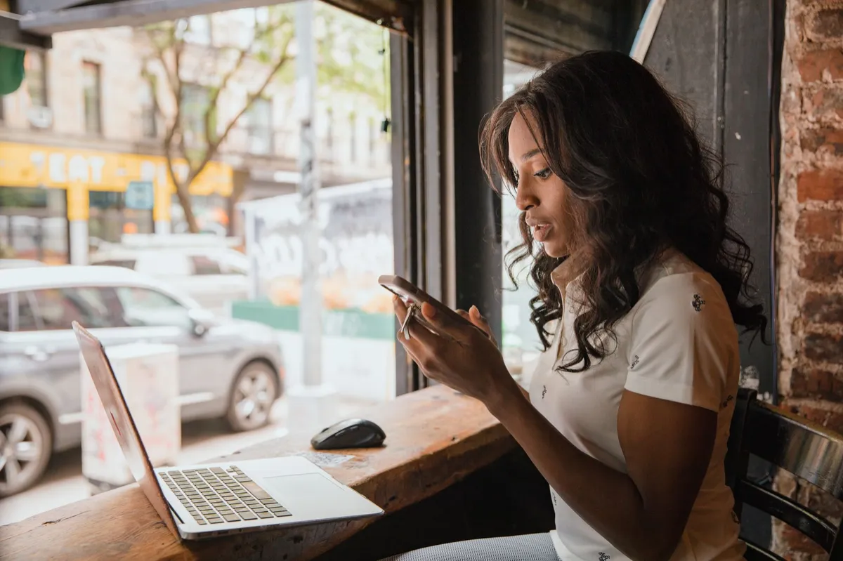 Employee checks smartphone beside work laptop, highlighting BYOD security risks for managed IT