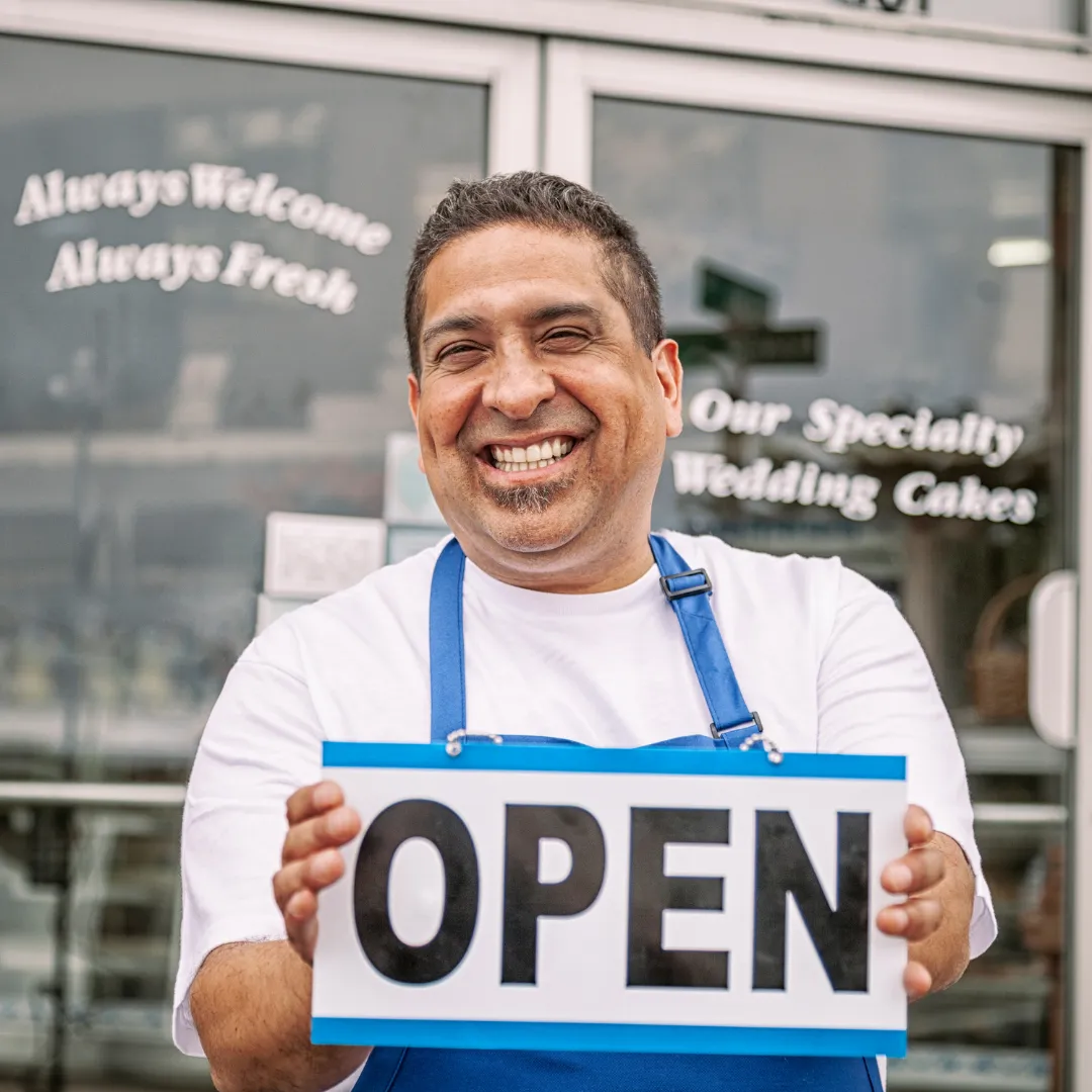 A Man Holding An Open Sign, Smiling