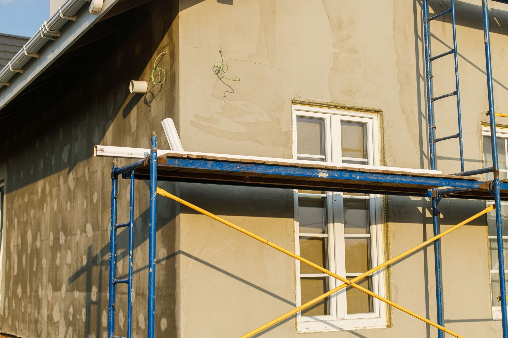 Travaux de ravalement de façade en cours avec échafaudage pour l'application de l'enduit sur un mur extérieur en Eure-et-Loir.
