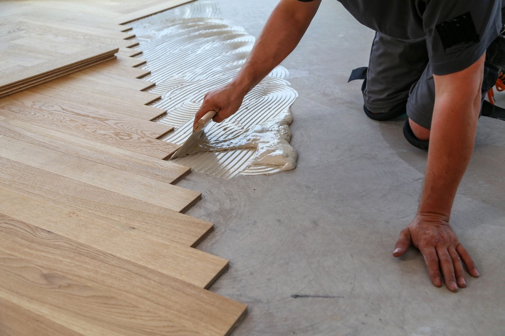 Parqueteur professionnel réalisant la pose collée d'un parquet en chêne massif sur un chantier à Dreux
