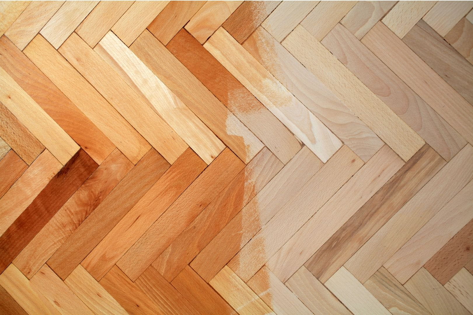 Application d'un vernis de vitrification sur un parquet en bâtons rompus montrant le contraste entre le bois mat et brillant.