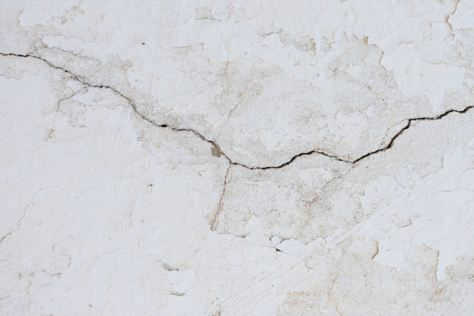 Artisan maçon appliquant un enduit de rebouchage sur une fissure de mur extérieur en Eure-et-Loir